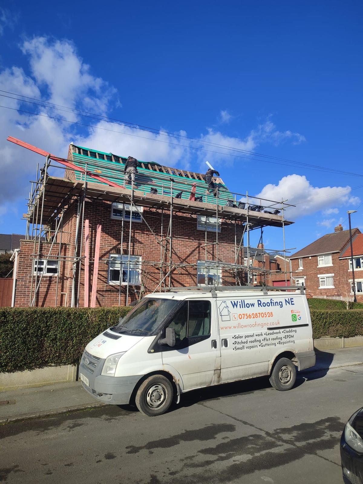 scaffolded gable and branded van, blue sky