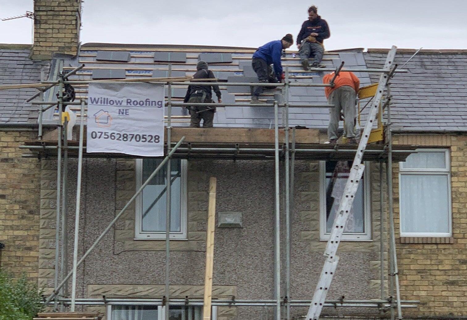 four-man crew slating on scaffold with site banner