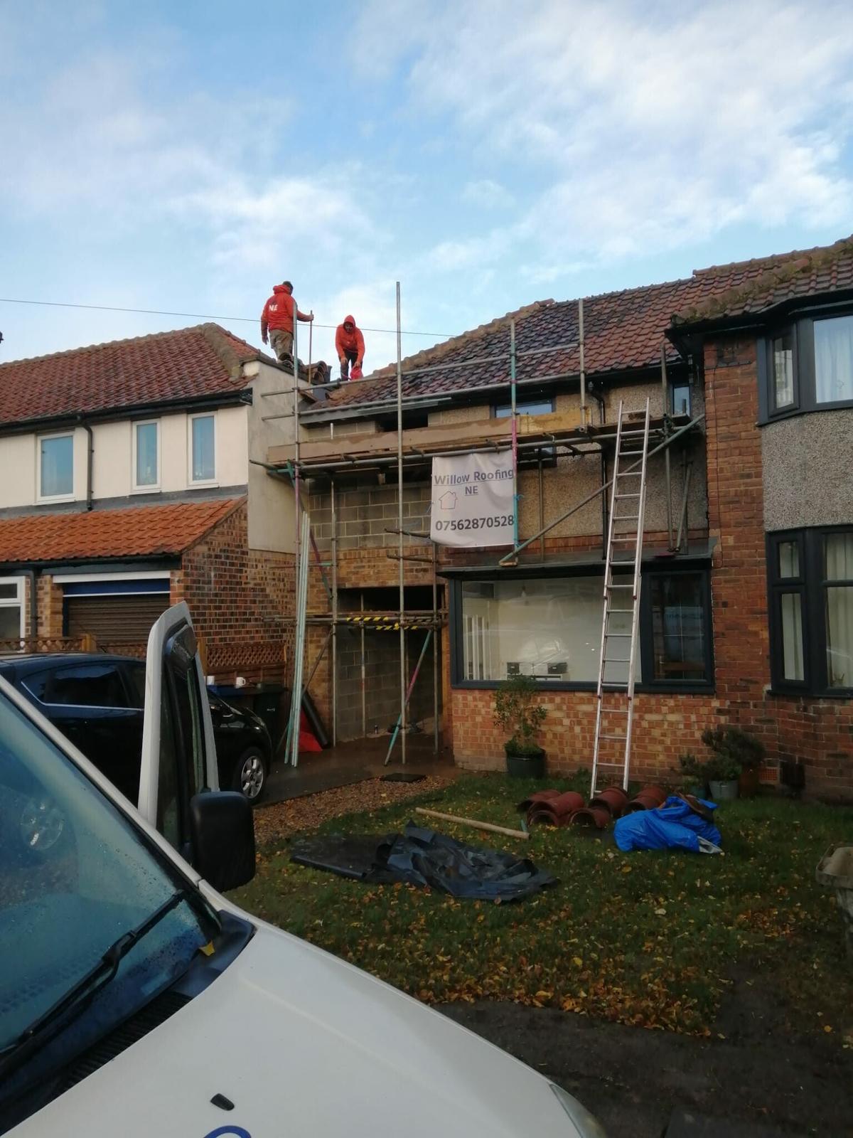 crew on scaffold at gable, site banner, sunshine