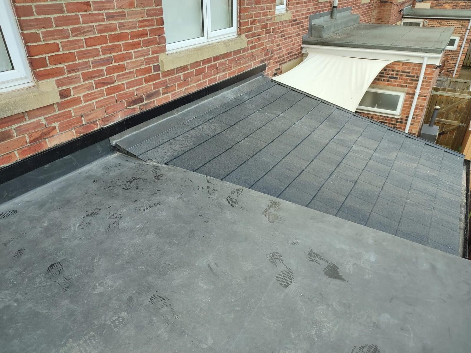 grey EPDM flat roof beside brick dormer, finished