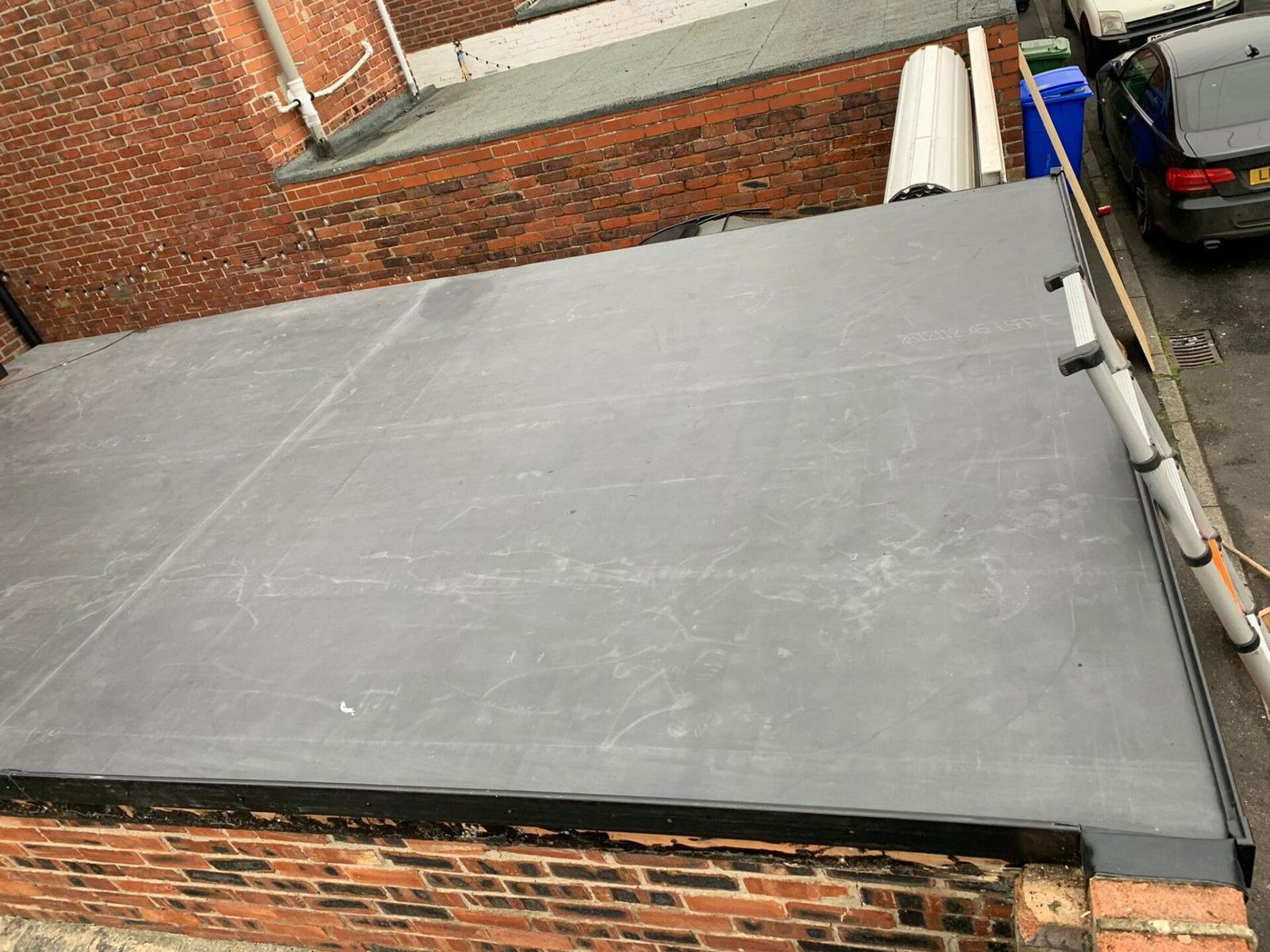 grey flat roof extension against brick terrace