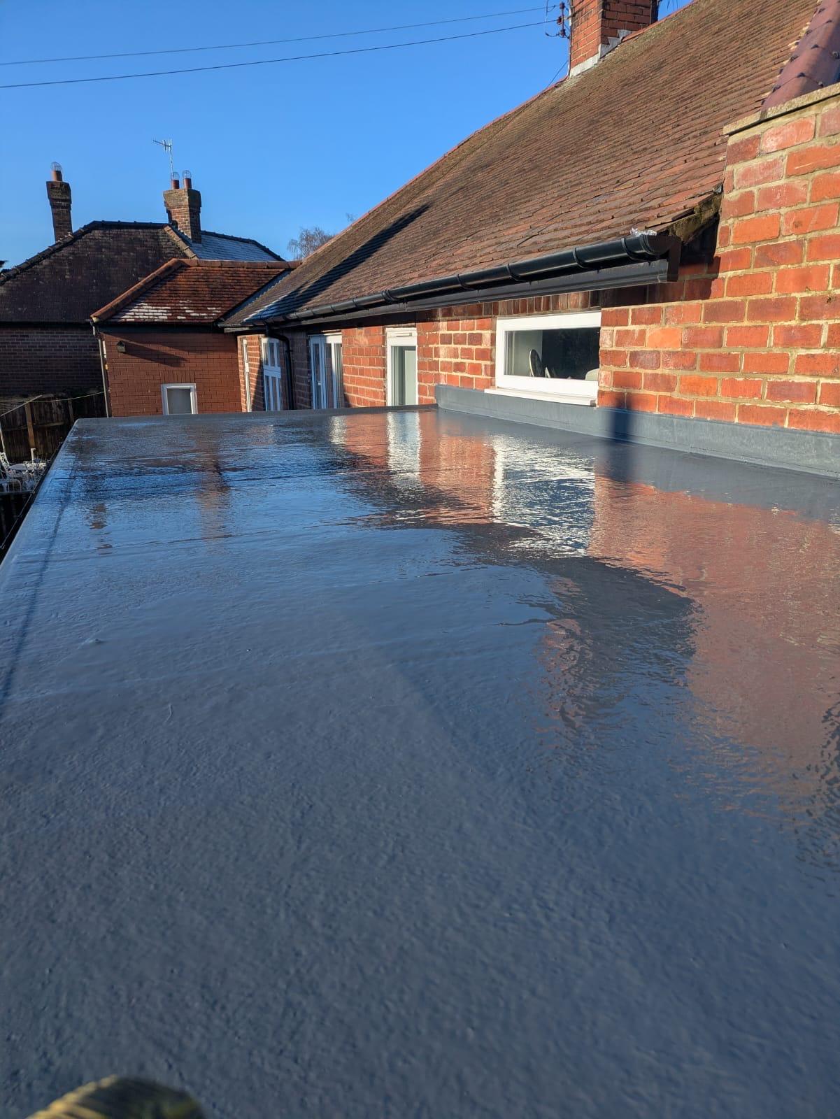 new grey GRP fibreglass flat roof on a rear extension, blue sky