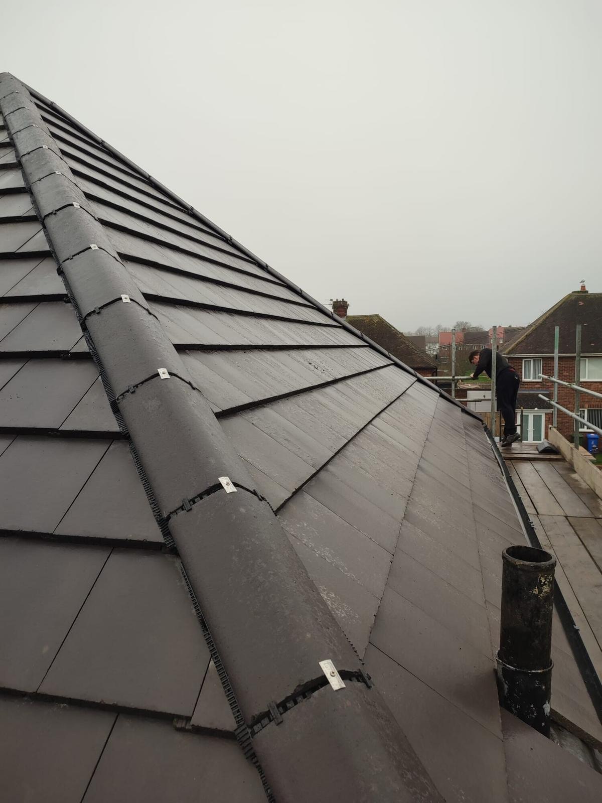 Long dark slate roof slope with dry ridge under a moody North East sky
