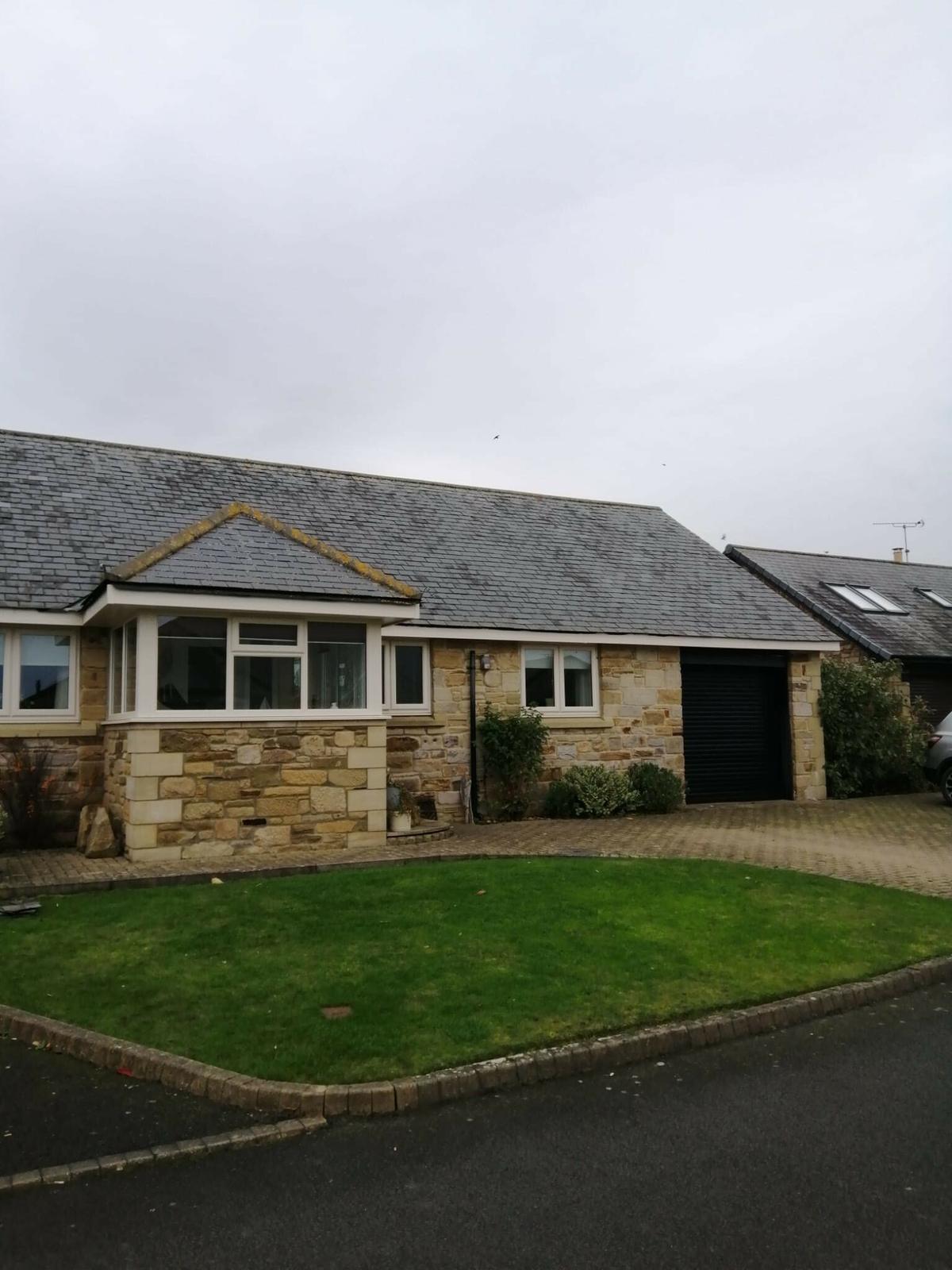stone bungalow with new grey slate roof, lawn frontage