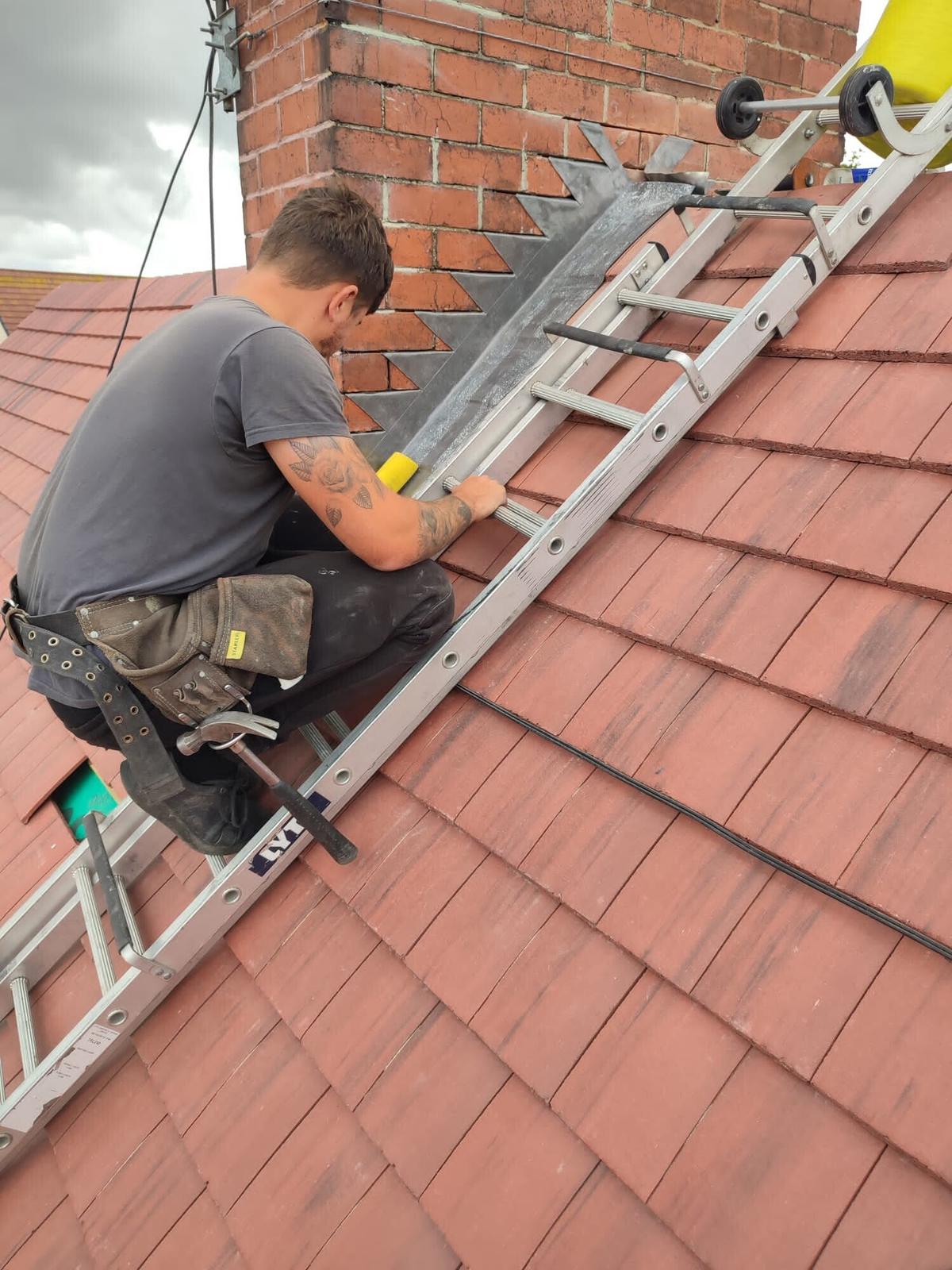 roofer repointing chimney off ladder, red tiles