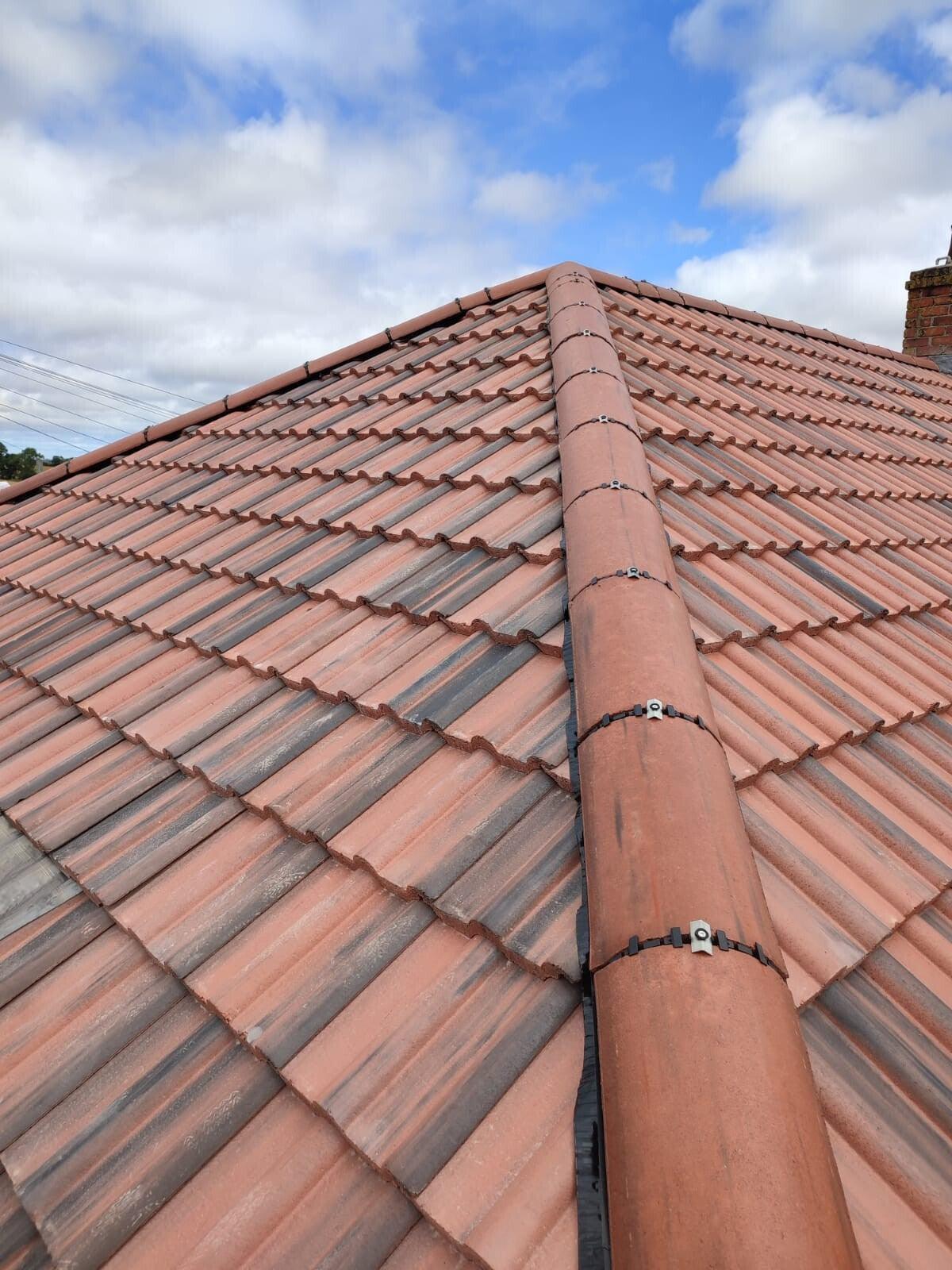 red pantile hip roof with fresh ridge, cloudy sky — recent Willow Roofing work