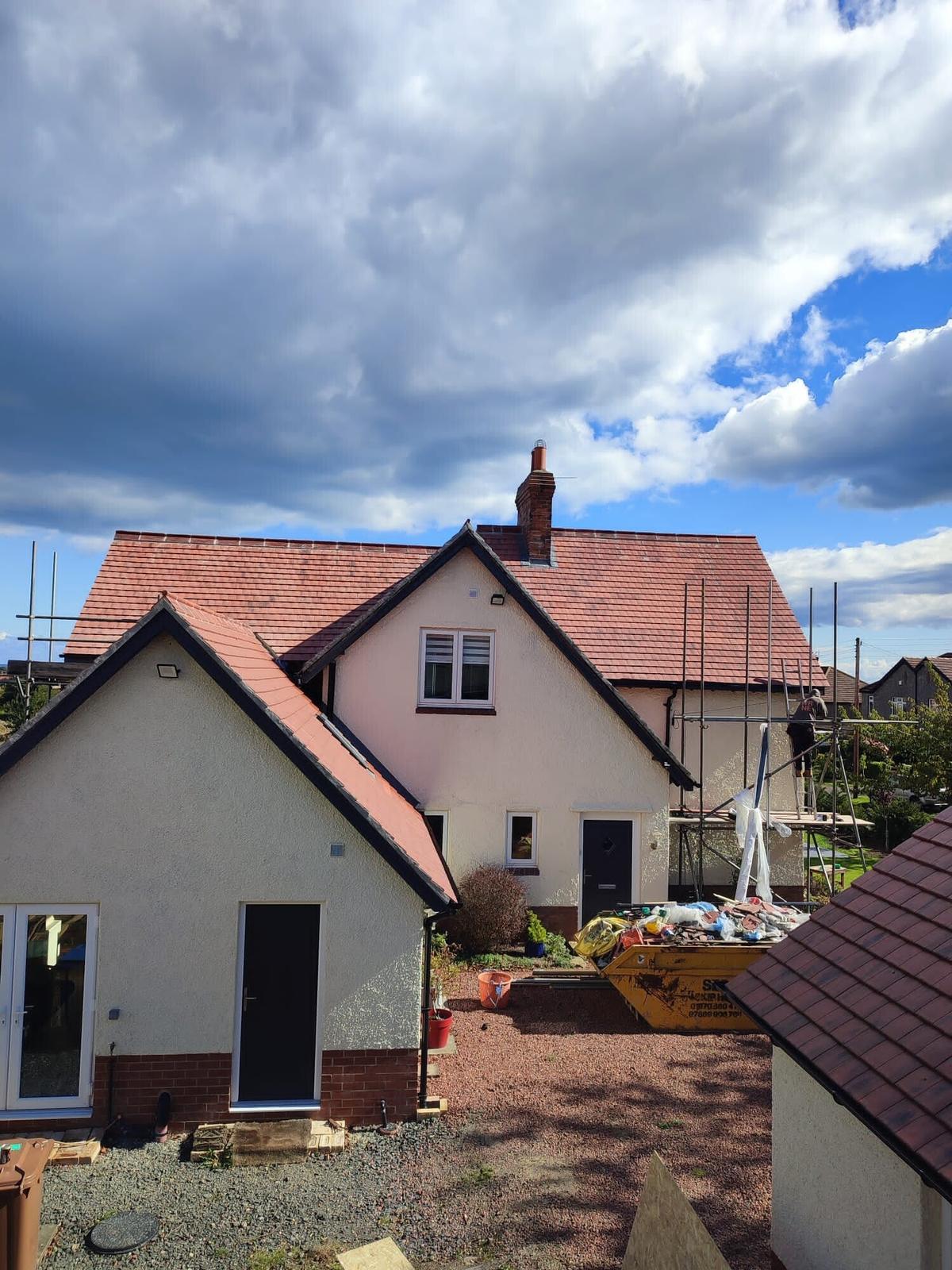 pink render bungalow with new red tile roof, blue sky