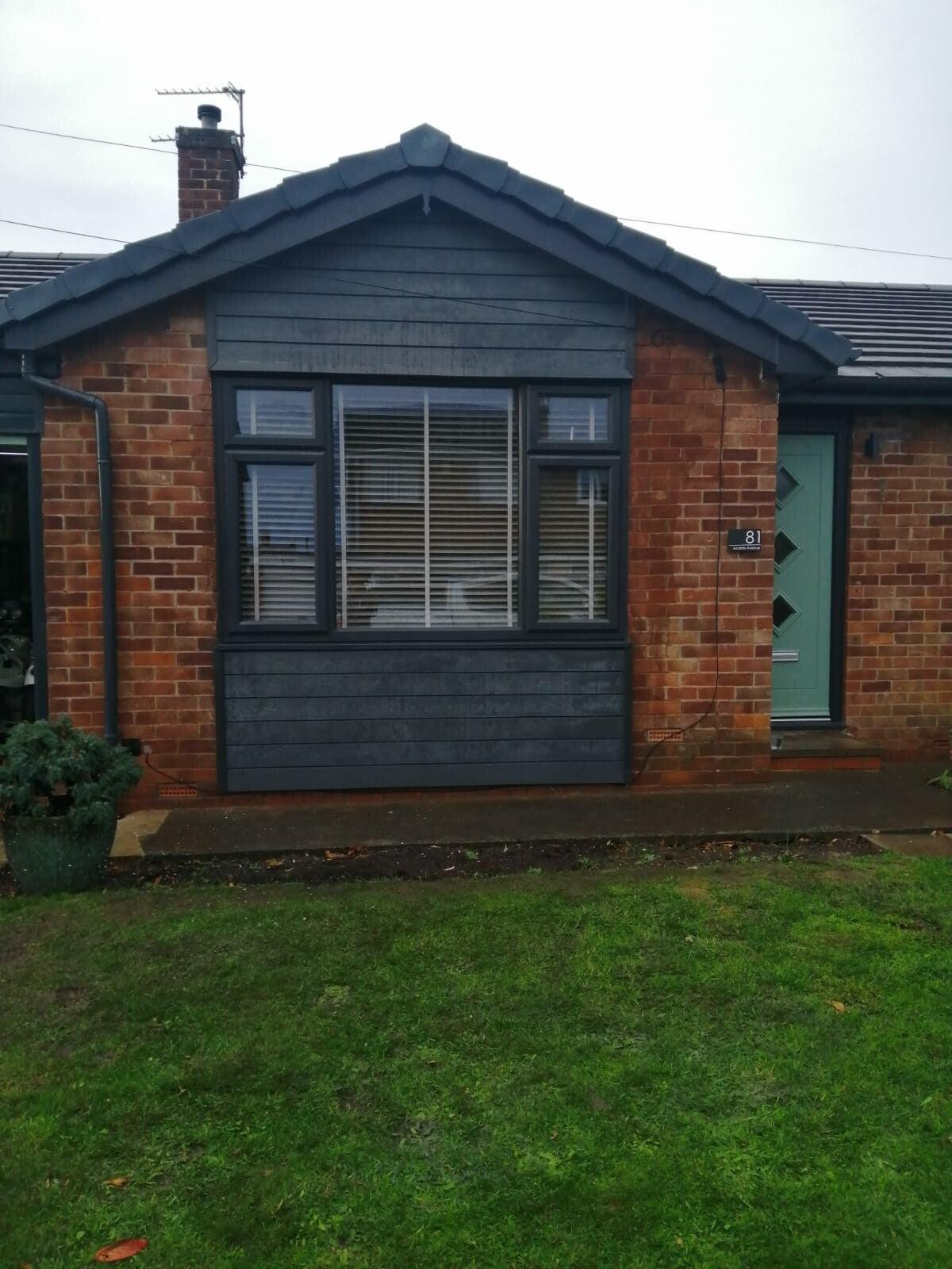 bungalow with dark grey cladding and brick, lawn
